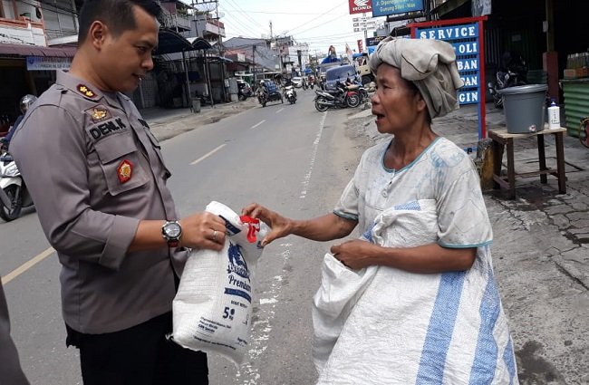 Kapolres Nias AKBP Deni Kurniawan, saat membagikan sembako kepada salah seorang pemulung di Kota Gunungsitoli, Minggu (5/4/2020)/Foto:dok.Humas Polres Nias