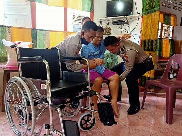 Kanit Reg Ident Sat Lantas Iptu Sonahami Lase dibantu personel sedang memapah Sarotona Telaumbanua ke kursi roda pemberian Kapolres Nias AKBP Deni Kurniawan, Selasa (7/7/2020)/Foto: Humas Polres Nias